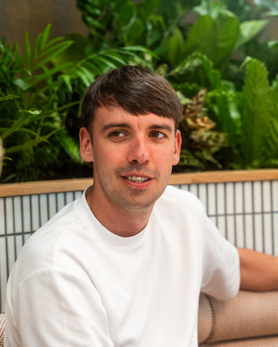 A colleague chatting on the sofa surrounded by plants in the Leadly office