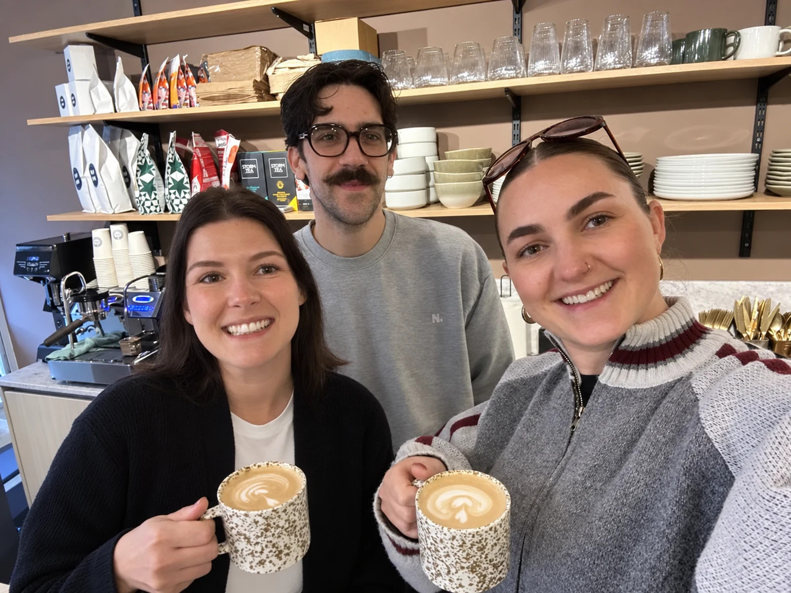 Three colleagues with lattes at the office coffee counter