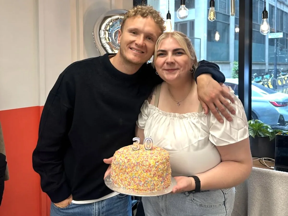 Two colleagues celebrating a 30th birthday with a sprinkle cake