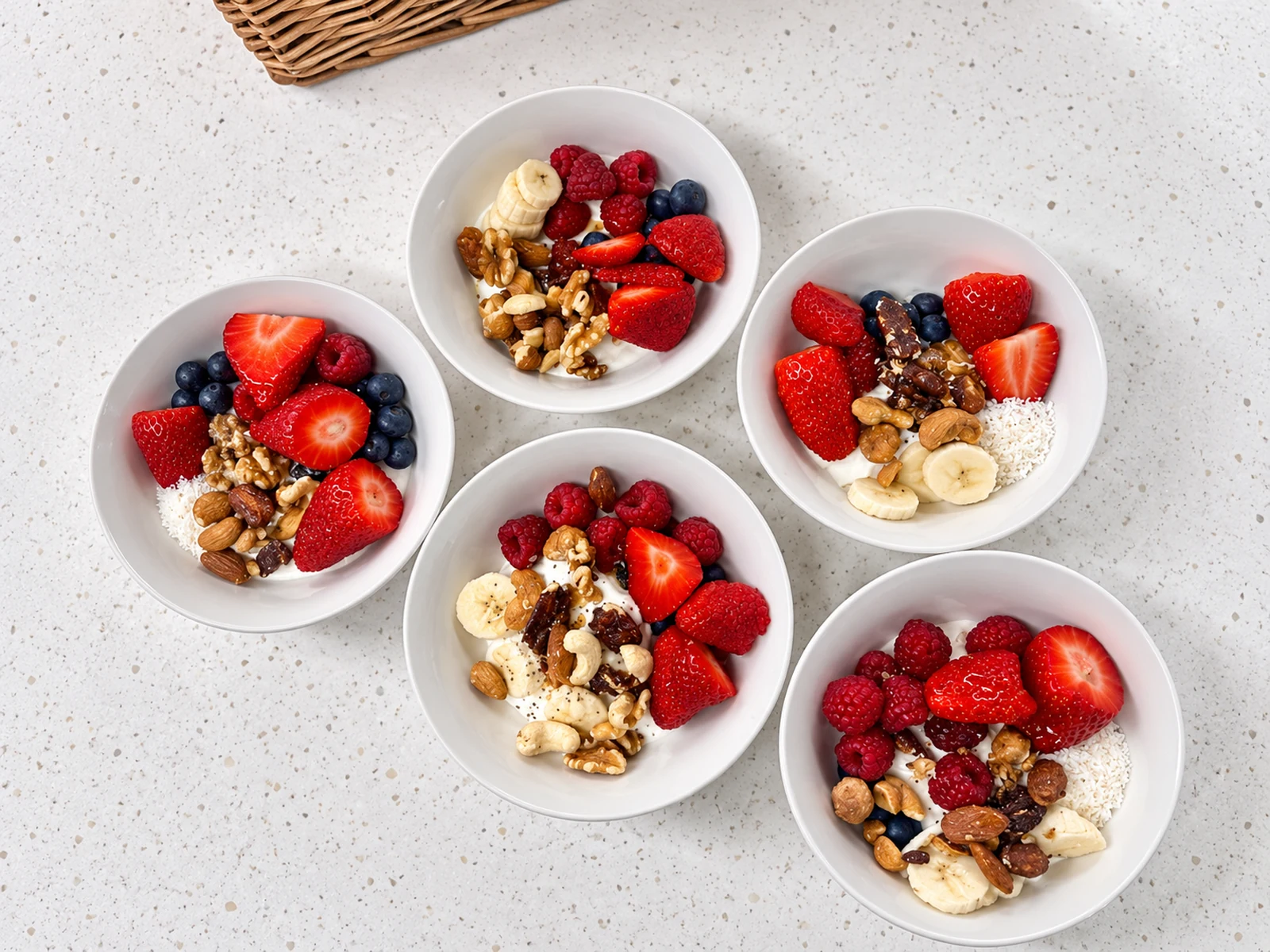 Four bowls of yoghurt with fresh berries, nuts and banana from the free office breakfast