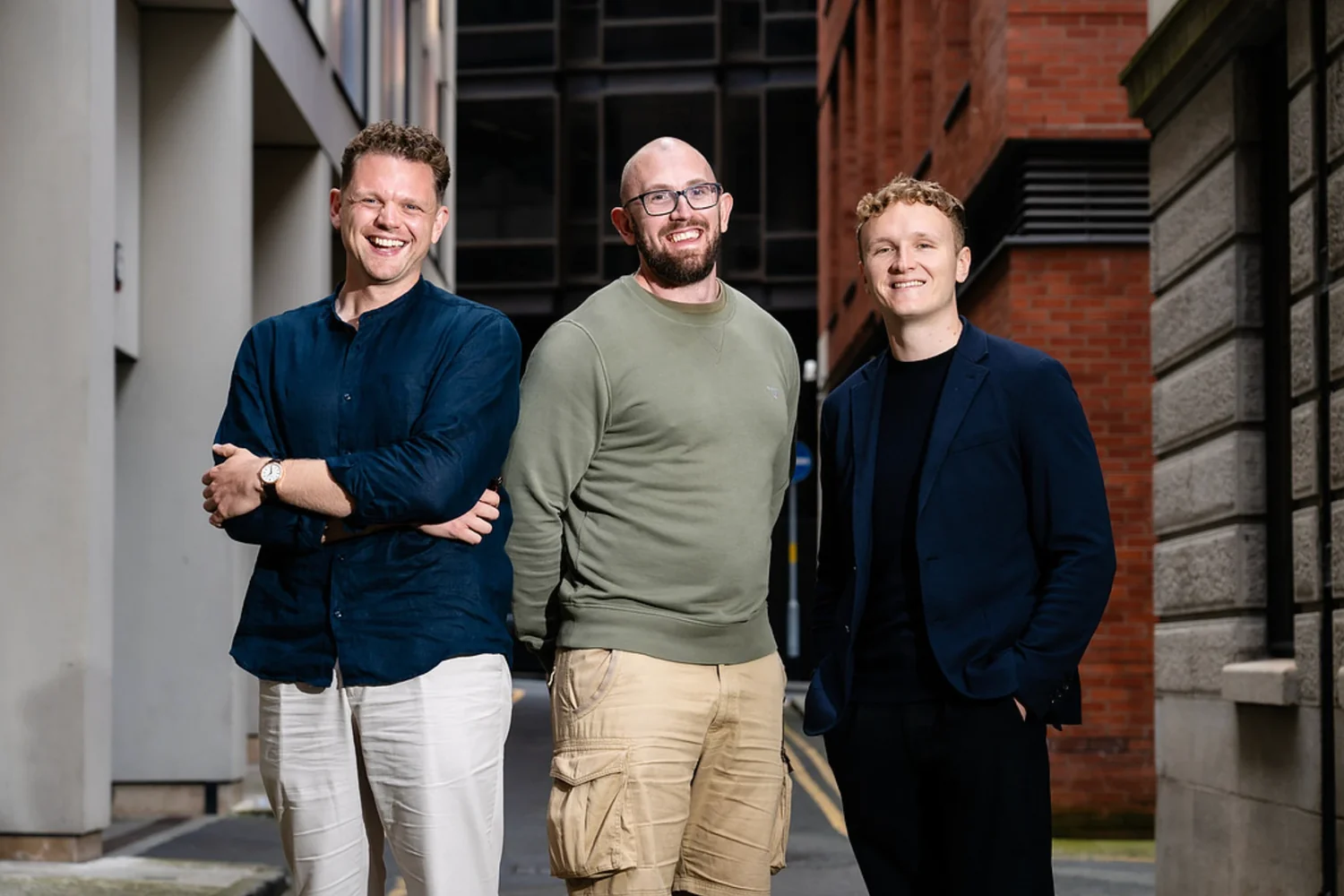 Three members of the Leadly team smiling in a Manchester side street